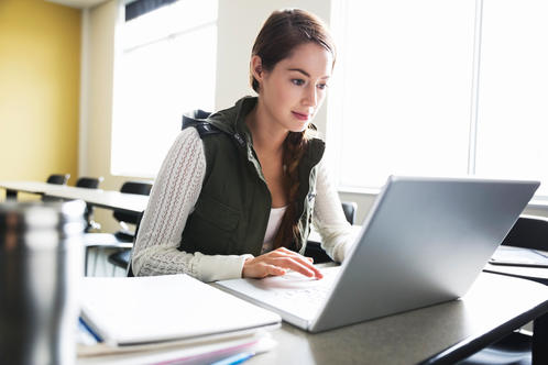 Female student working on laptop in college classroom